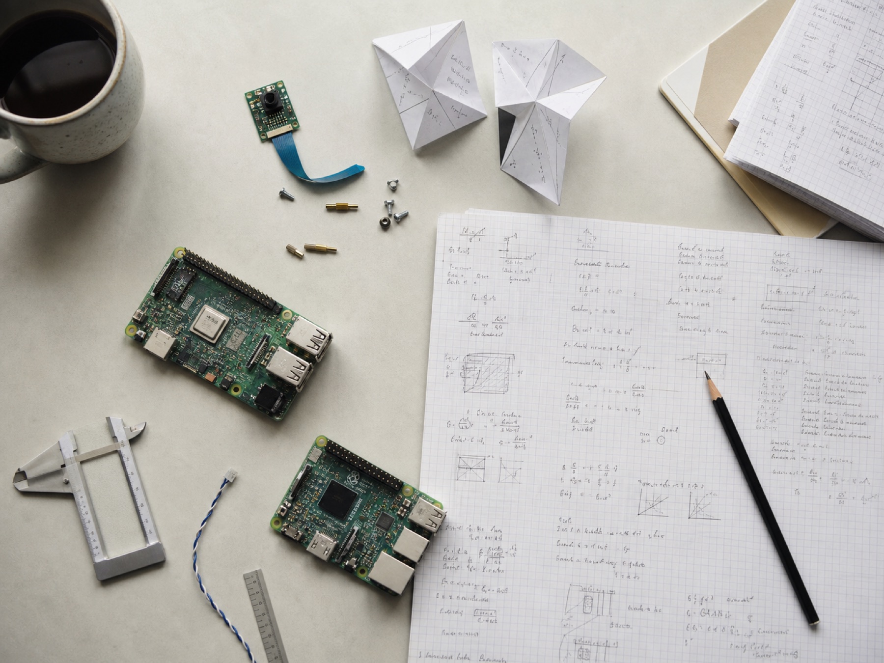 Electronics, handwritten research notes, and prototype parts on a lab workbench